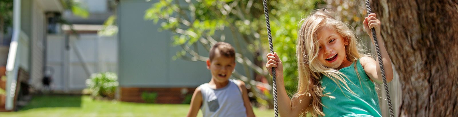two kids playing on an outside swing