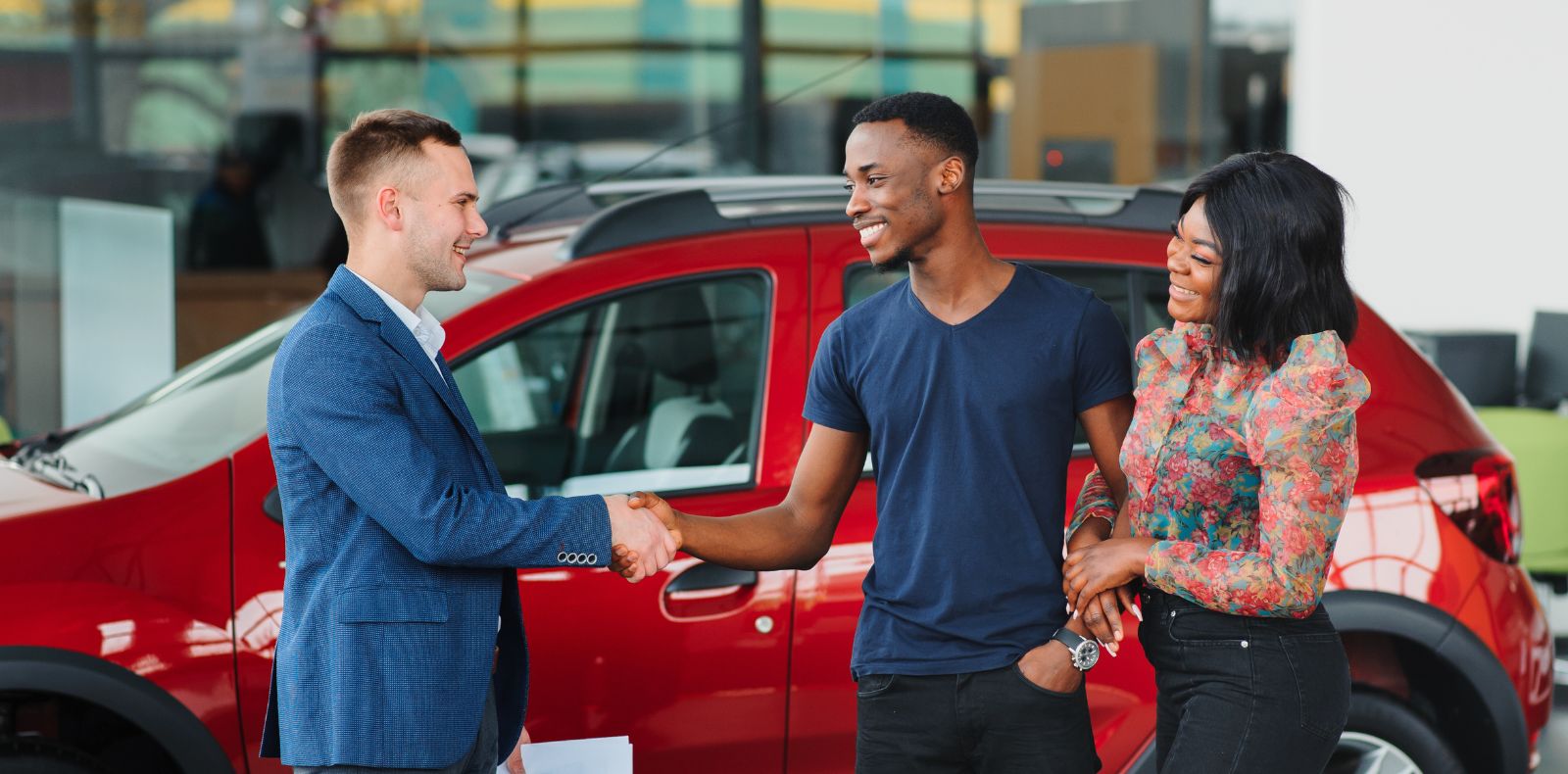 a couple shaking hands with an auto sales representative
