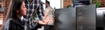 Two people looking at two monitors