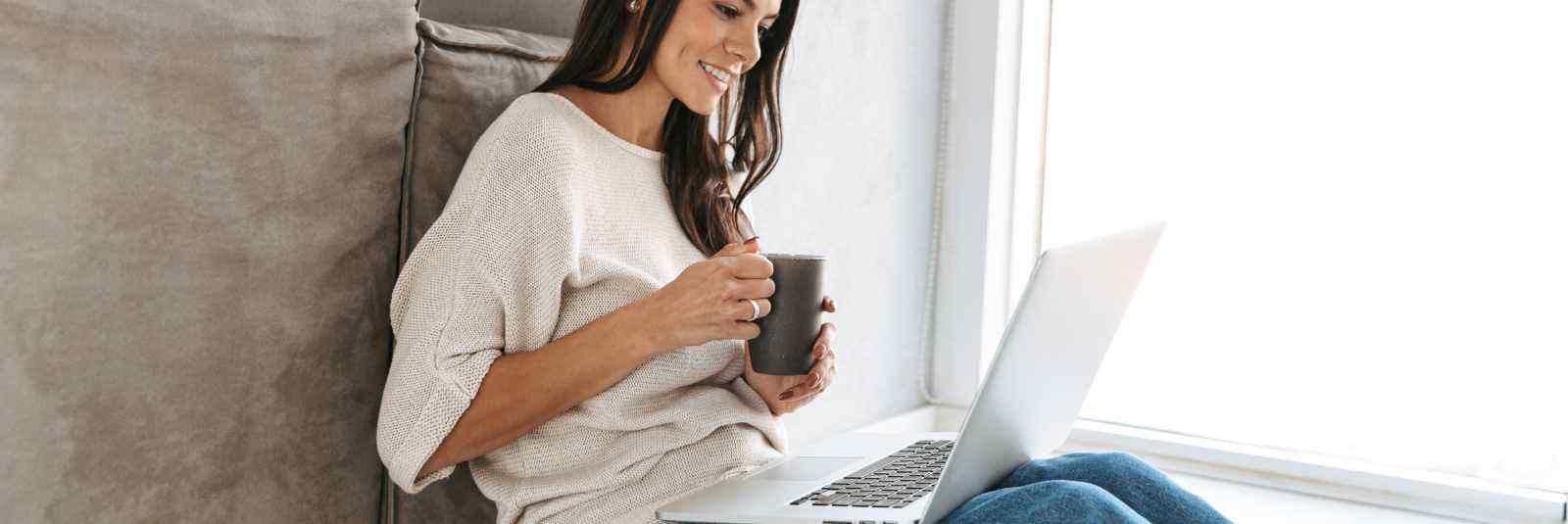 woman holding coffee up on her laptop