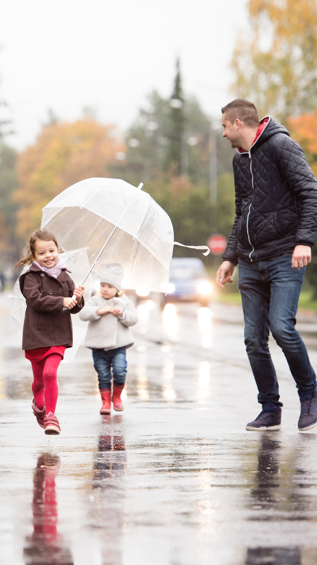 a father and his daughters walking in the rain with an umbrella