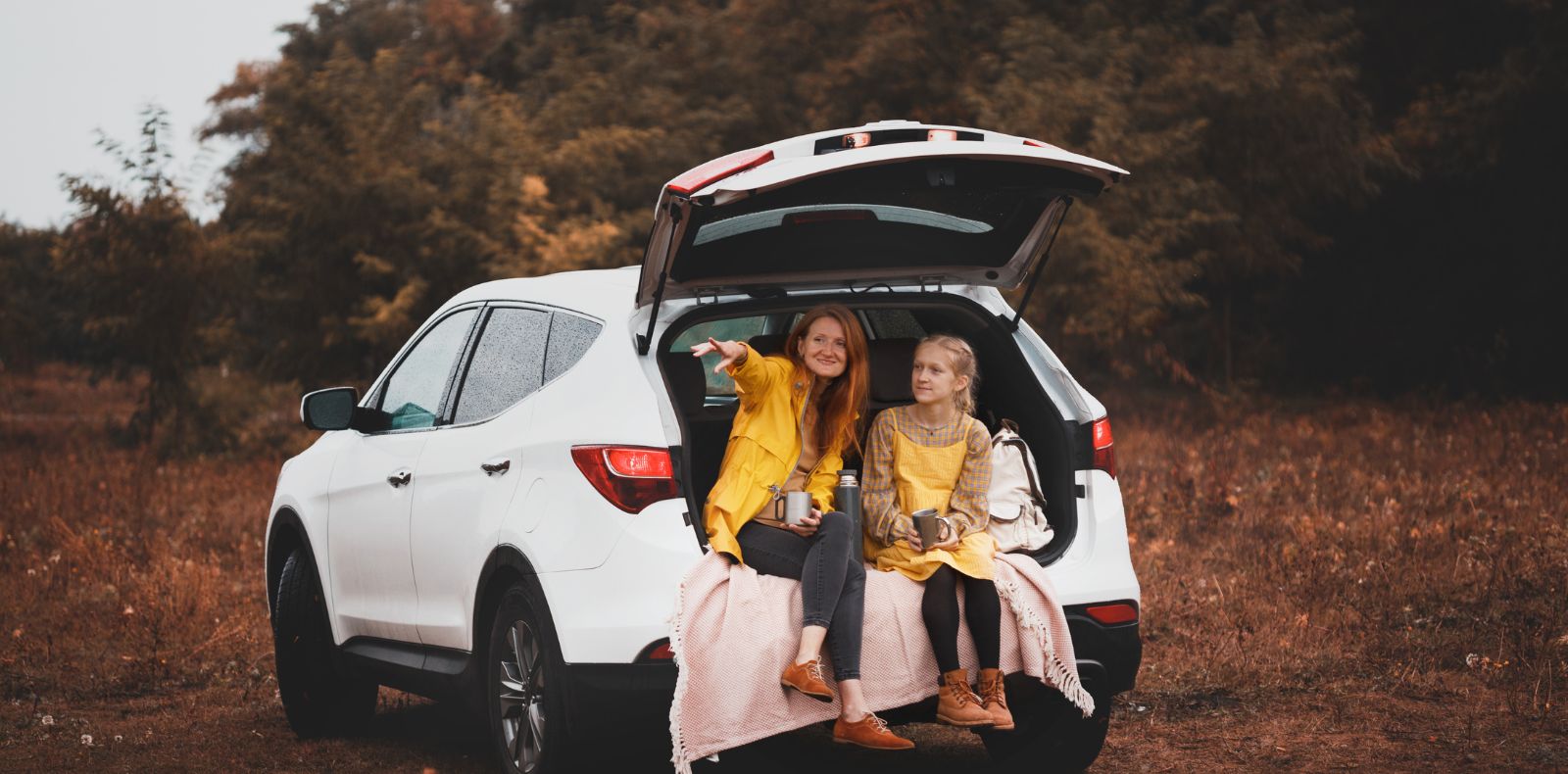 a mother and daughter sitting in the back of an automobile