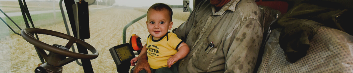 a little boy sitting on a person's lap in a tractor